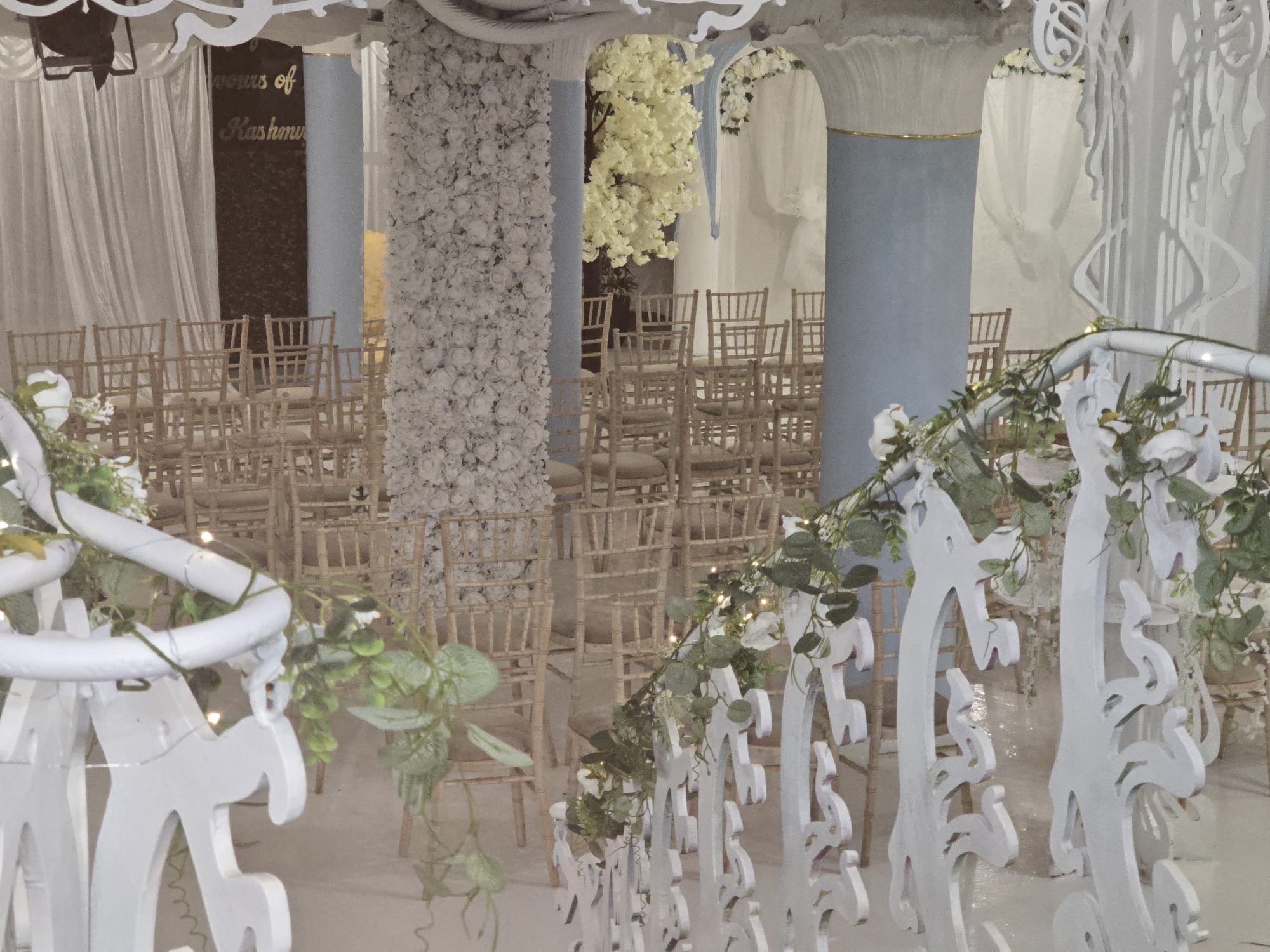 Limewash Chiavari chairs facing a white rose floral column and cherry blossom stage inside the Grade II listed Opulent @ 35 Liverpool ceremony hall
