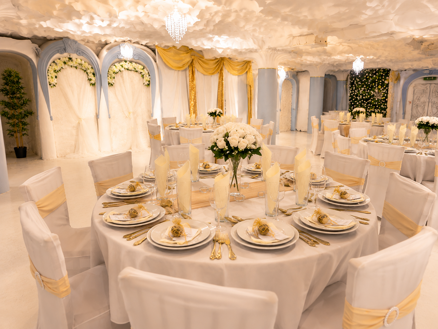 Round banquet tables beneath gold drapery, pale blue arches and floral backdrops at Opulent @ 35 Liverpool